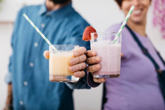 Pareja con vasos de diferentes batidos listos para beber, vista parcial