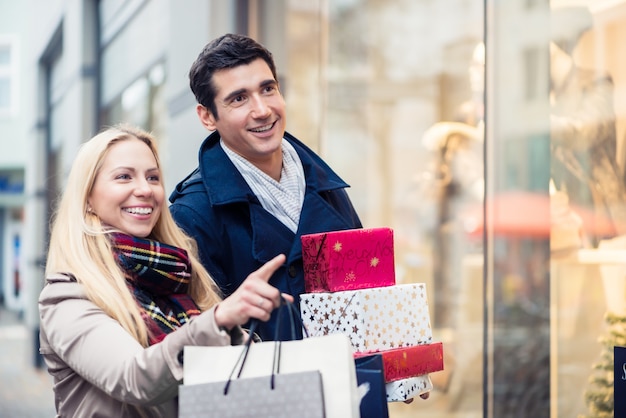 Pareja en la ventana de la tienda haciendo compras de Navidad