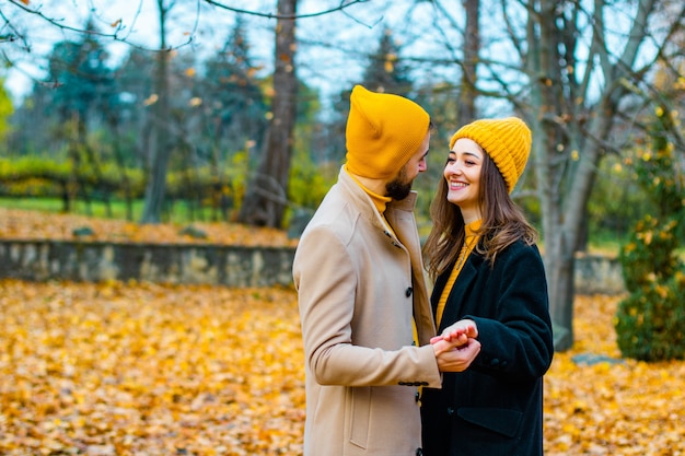 Pareja vestida con cuellos de tortuga amarillos y sombreros amarillos en el parque en otoño