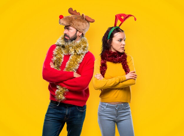 Pareja vestida para las fiestas navideñas con dudas y con cara de confusión.