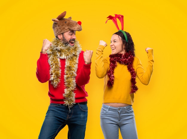 Pareja vestida para las vacaciones de Navidad celebrando una victoria en la posición de ganador