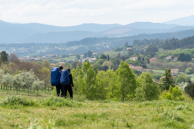 Una pareja viaja con mochilas por el campo.