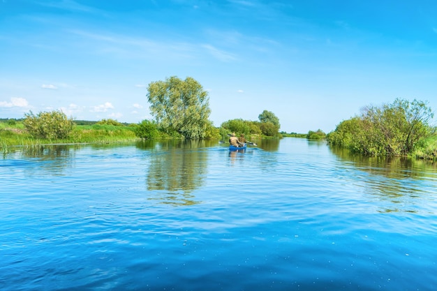 Pareja en viaje en kayak en el paisaje del río azul y bosque verde con árboles cielo de nubes de agua azul
