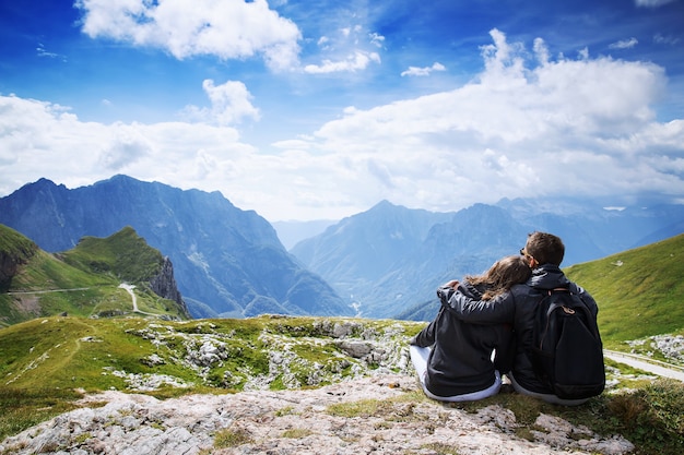 Pareja de viajeros excursionistas en la cima de una montaña disfrutando de vistas al valle