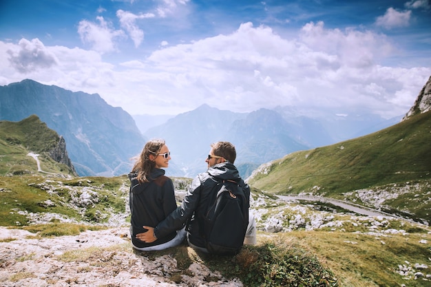 Pareja de viajeros excursionistas en la cima de una montaña disfrutando de vistas al valle