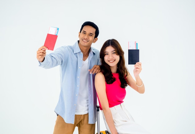 Pareja de viajeros en felices vacaciones Concepto de luna de miel de vacaciones de verano Sonriente pareja asiática sosteniendo y mostrando pasaporte listo para viajar retratos de mujer y hombre jóvenes aislados en fondo blanco