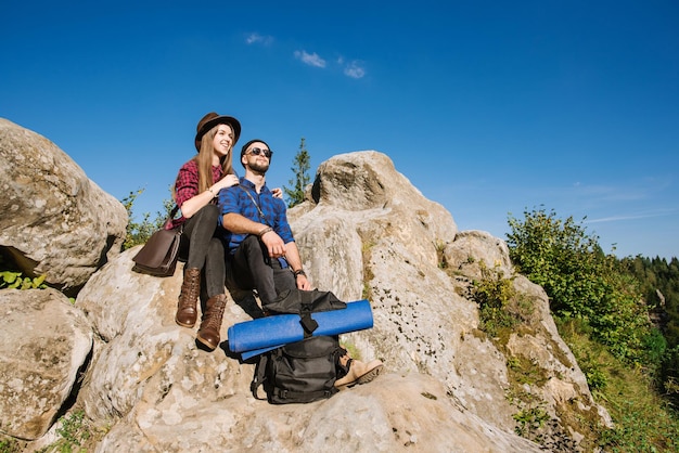 Una pareja de viajeros hipster sentados juntos en las rocas de las montañas