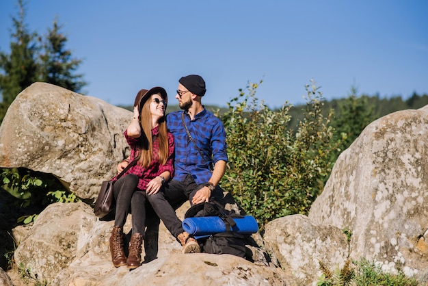 Una pareja de viajeros hipster sentados juntos en las rocas de las montañas