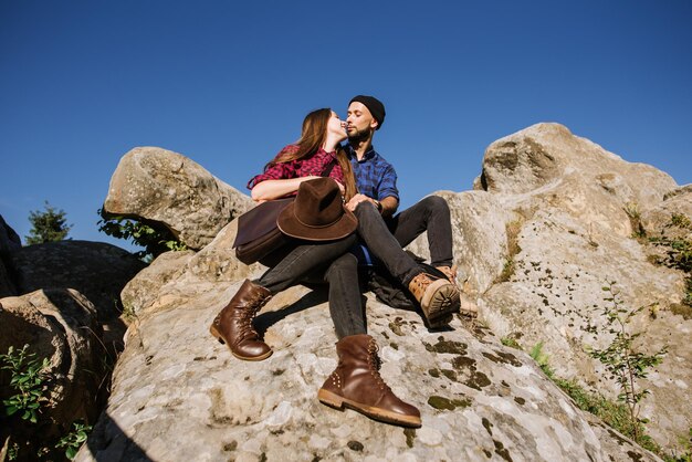 Una pareja de viajeros hipster sentados juntos en las rocas de las montañas