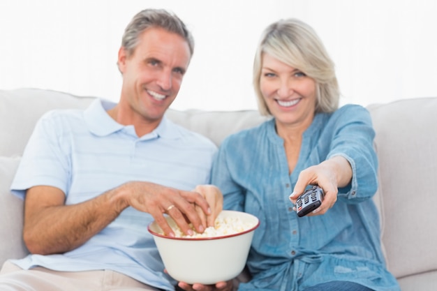 Pareja viendo la televisión y comiendo palomitas de maíz en el sofá