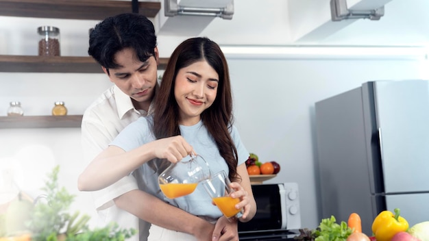 Una pareja vierte jugo de naranja en su cocina.