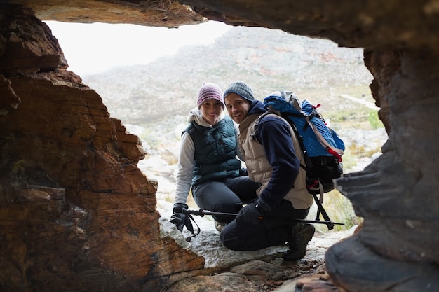 Pareja vista a través de la cueva de roca en una caminata