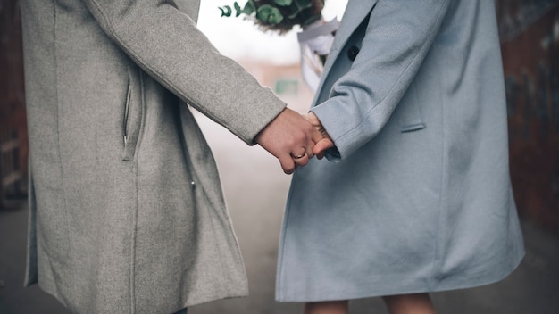 Foto pareja vistiendo un abrigo tomados de la mano