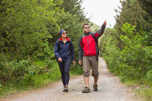 Pareja yendo de excursión junto con hombre señalando