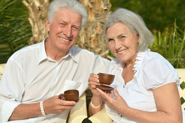 Las parejas ancianas descansando en el resort durante las vacaciones con tazas de té