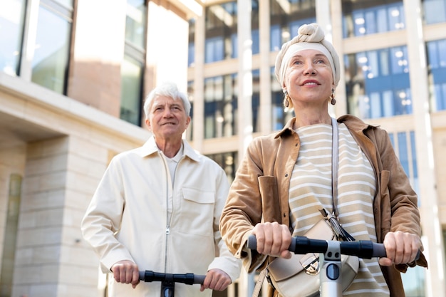 Las parejas ancianas montando un scooter eléctrico en la ciudad