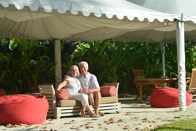 Las parejas ancianas sentadas en un banco de madera con una almohada en el resort