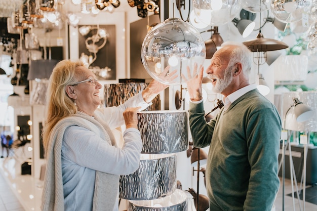 Las parejas ancianas en la tienda de iluminación para el hogar shoosing shandelier para su hogar