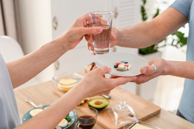 Las parejas ancianas tomando pastillas con agua antes del desayuno estilo de vida saludable