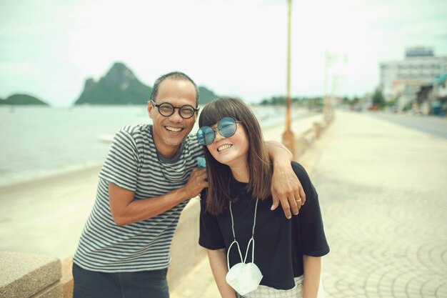 Parejas de Asia de mediana edad riendo con felicidad, de pie junto a la playa