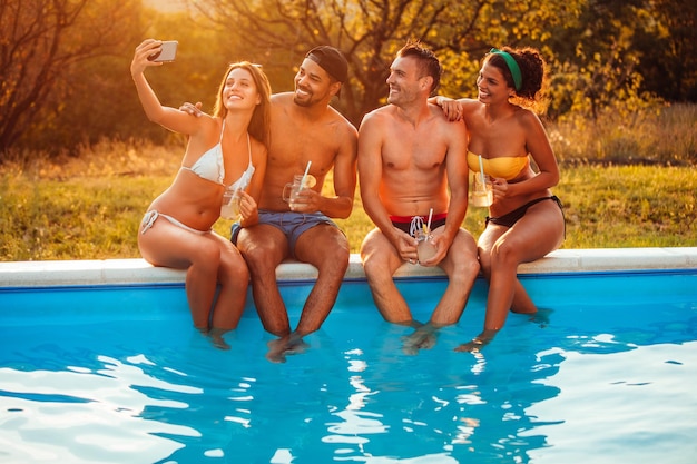 Parejas hablando selfie junto a la piscina Tonos cálidos