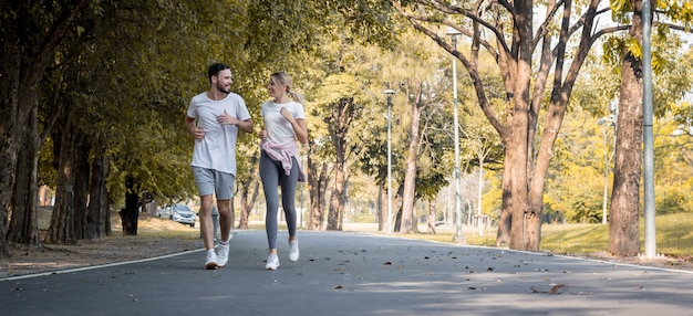 Las parejas hacen ejercicio en el parque. Parejas jovenes que hacen jogging en el parque. Las parejas corren por la carretera del parque.