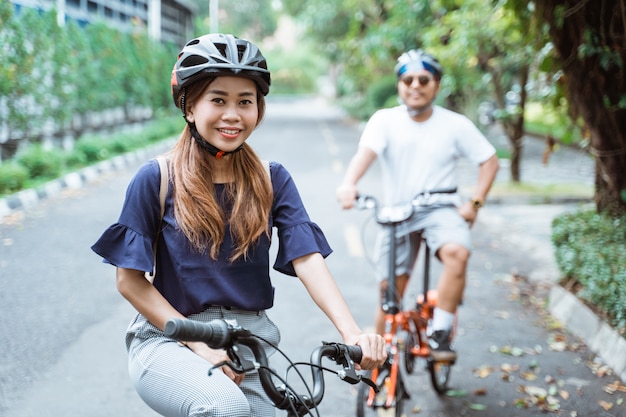 Las parejas jóvenes asiáticas que usan cascos disfrutan andar en bicicleta juntas