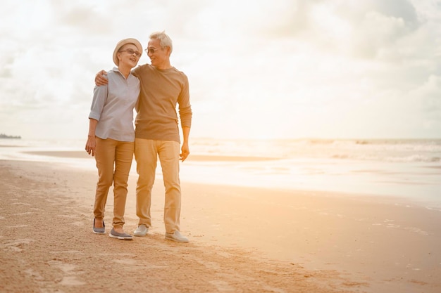 Las parejas mayores abrazan la playa al atardecer, planifican un seguro de vida con el concepto de jubilación feliz.