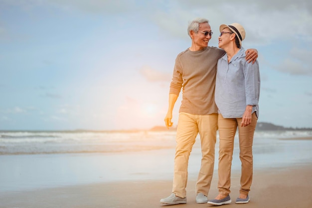 Las parejas mayores abrazan la playa del amanecer, planifican un seguro de vida con el concepto de jubilación feliz.