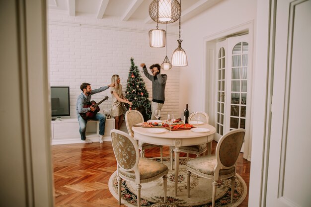 Parejas que cuelgan adornos navideños en el árbol.