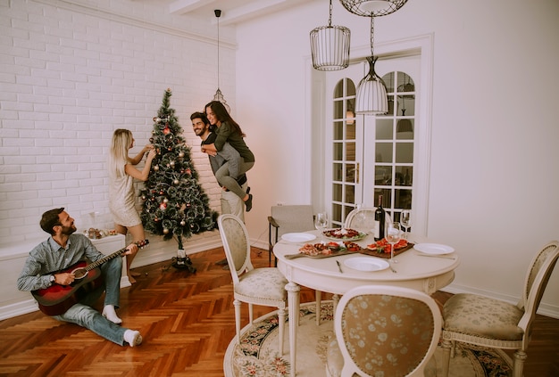 Parejas que cuelgan adornos navideños en el árbol.