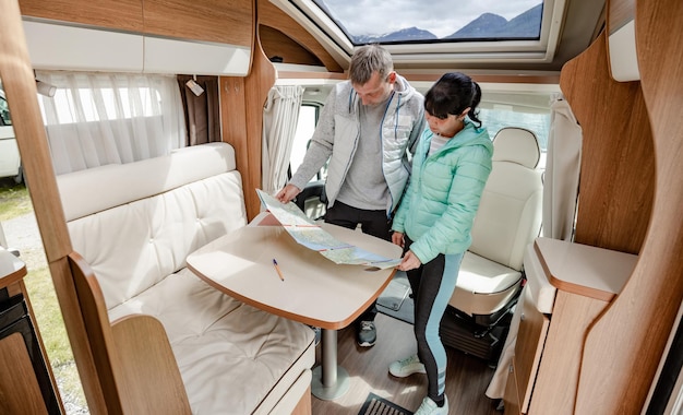 Parejas en RV Camper mirando el mapa local para el viaje. Viaje de vacaciones en familia, viaje de vacaciones en autocaravana, autocaravana de vacaciones.