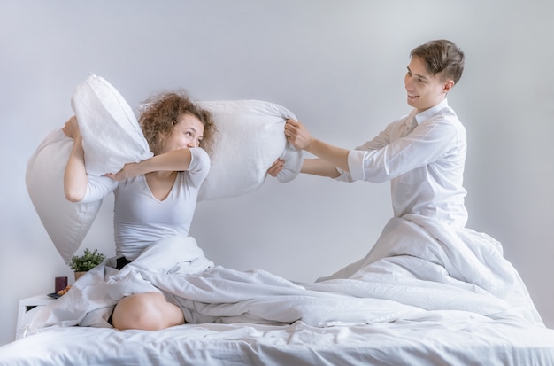 Foto las parejas usan una almohada para bromear entre sí en la cama.