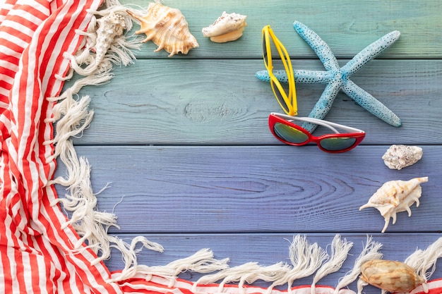 pareos com franjas de fundo de verão, conchas, óculos de sol, estrelas do mar em um fundo azul de madeira