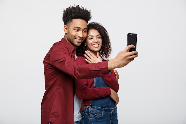 Los pares afroamericanos atractivos jovenes presentan para la actitud del selfie con el teléfono elegante