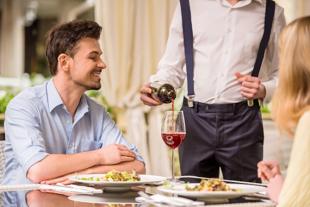 Pares alegres em um restaurante que pede o vinho.