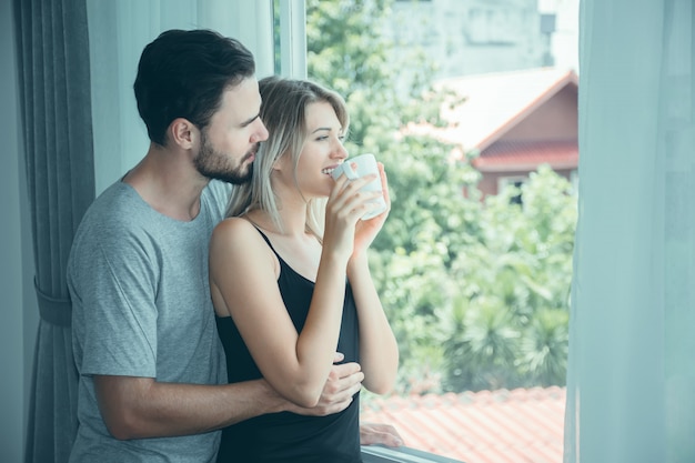 Pares en el amor que lleva a cabo las manos con café el mañana.