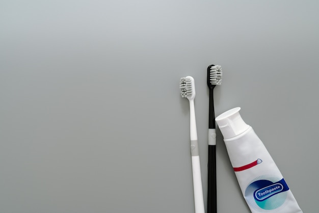 Pares del cepillo de dientes con crema dental en el fondo gris, concepto de la atención sanitaria