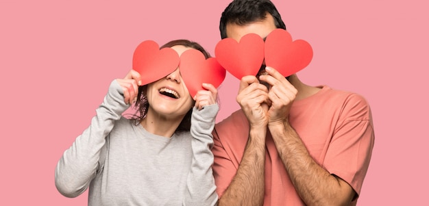 Pares en el día de San Valentín que lleva a cabo un símbolo del corazón sobre fondo rosado aislado