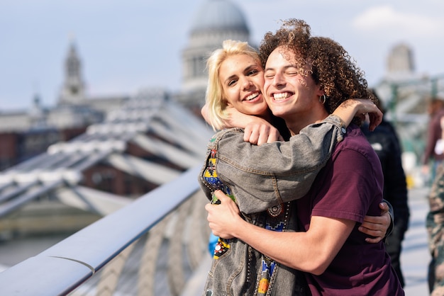 Pares felizes que abraçam pela ponte do milênio, rio tamisa, londres.