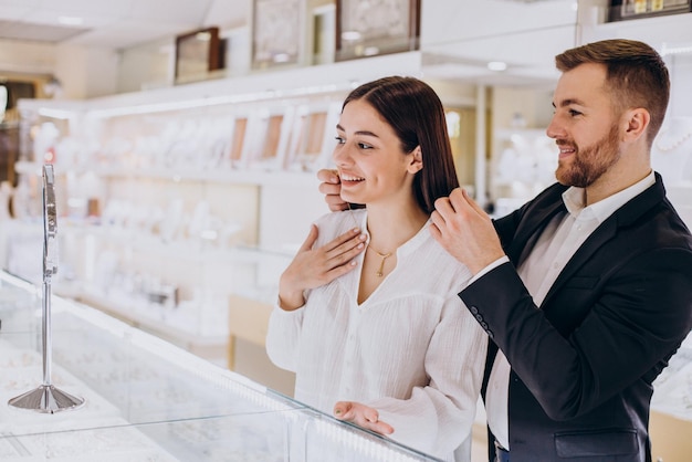 Foto pares jovenes que eligen un collar en la joyería