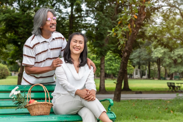 Pares mayores asiáticos con felicidad de la forma de vida de la cesta de fruta en parque.