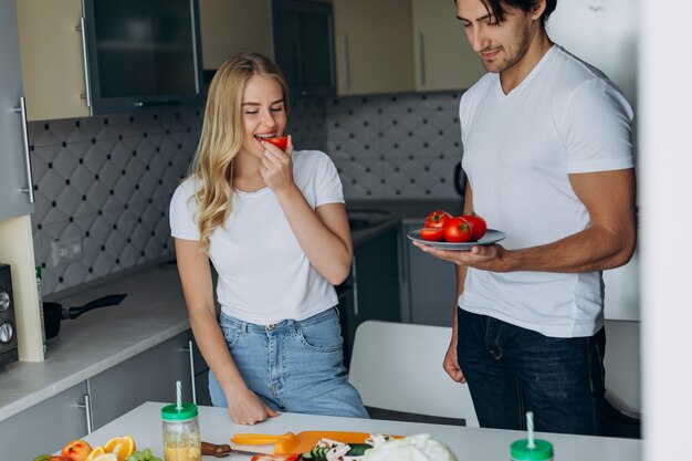 Pares na cozinha que está com alimento saudável. Mulher, comer, tomate