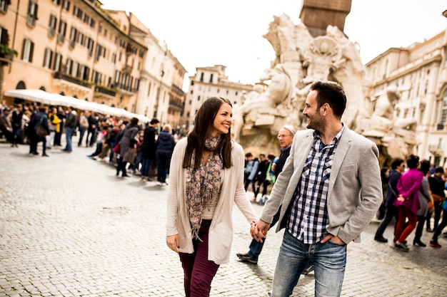 Pares novos ocasionais que guardam as mãos que andam em Roma, Itália, Europa.