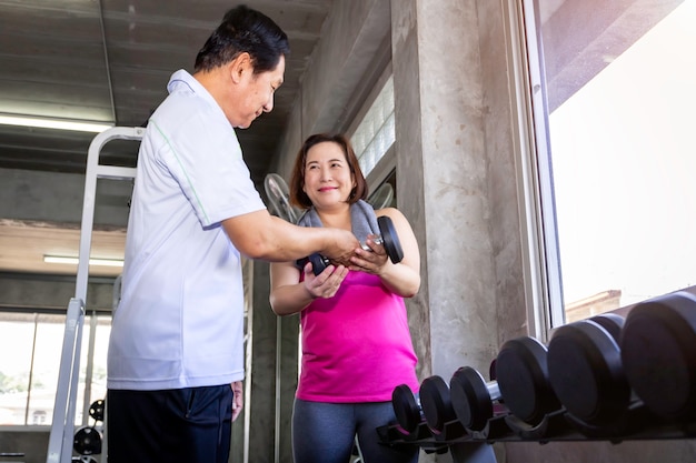 Pares sênior asiáticos que sorriem no sportswear que exercita na ginástica.