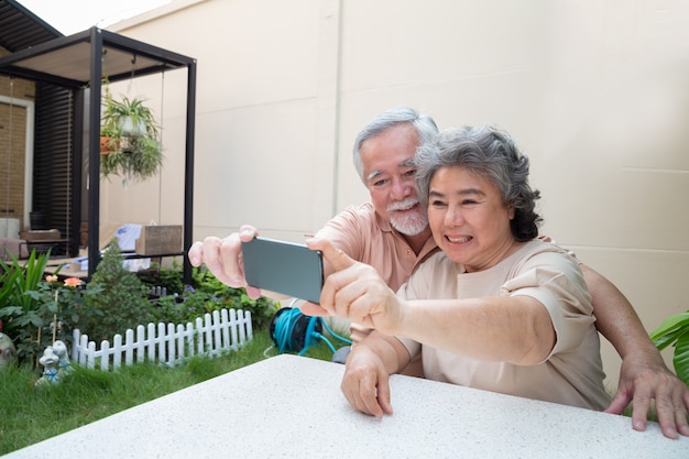 Foto pares sênior asiáticos que tiram uma foto do selfie junto com o smartphone em casa.