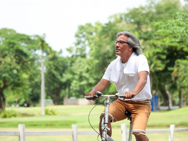 Pares sênior que cyling no parque. Conceito de cuidados de saúde.