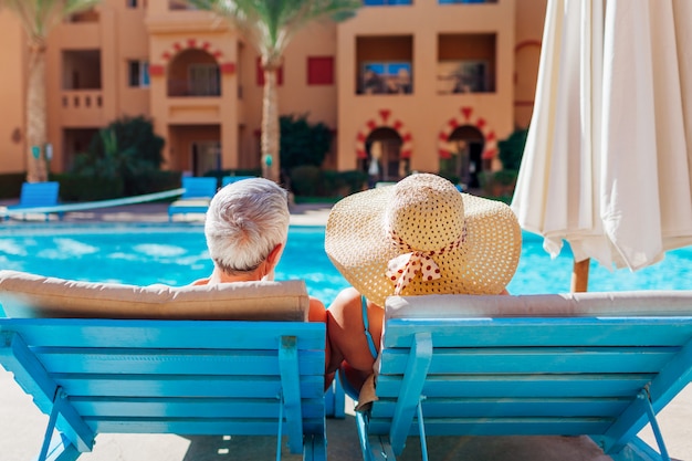 Pares sênior que relaxam pela piscina. Pessoas curtindo férias. Dia dos namorados