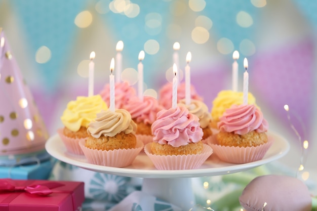 Párese con deliciosos cupcakes de cumpleaños en la mesa