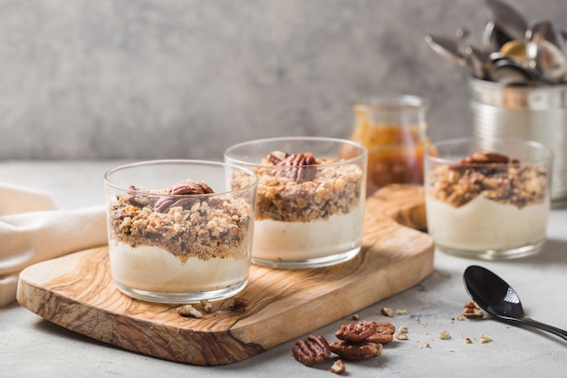 Parfait de iogurte natural delicioso com caramelo, nozes pecan em fundo conctere